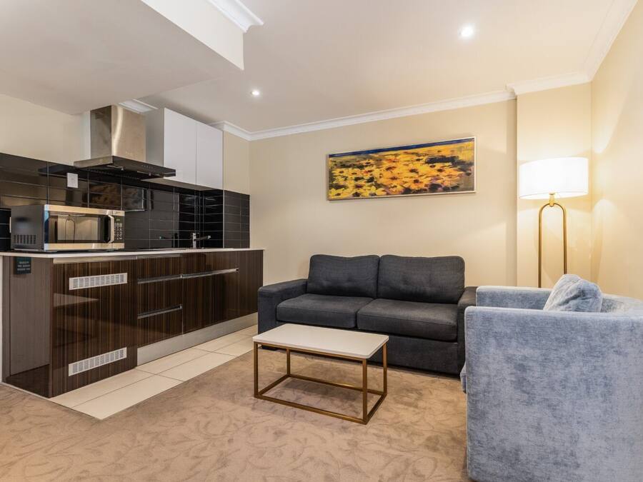 A compact living space with a kitchenette, a gray sofa, a small table, and a floor lamp.