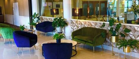 A spacious lobby with modern furniture, large windows, and decorative plants.