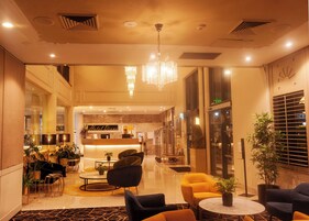 Una hall d'albergo moderna con reception, area salotto e un lampadario.