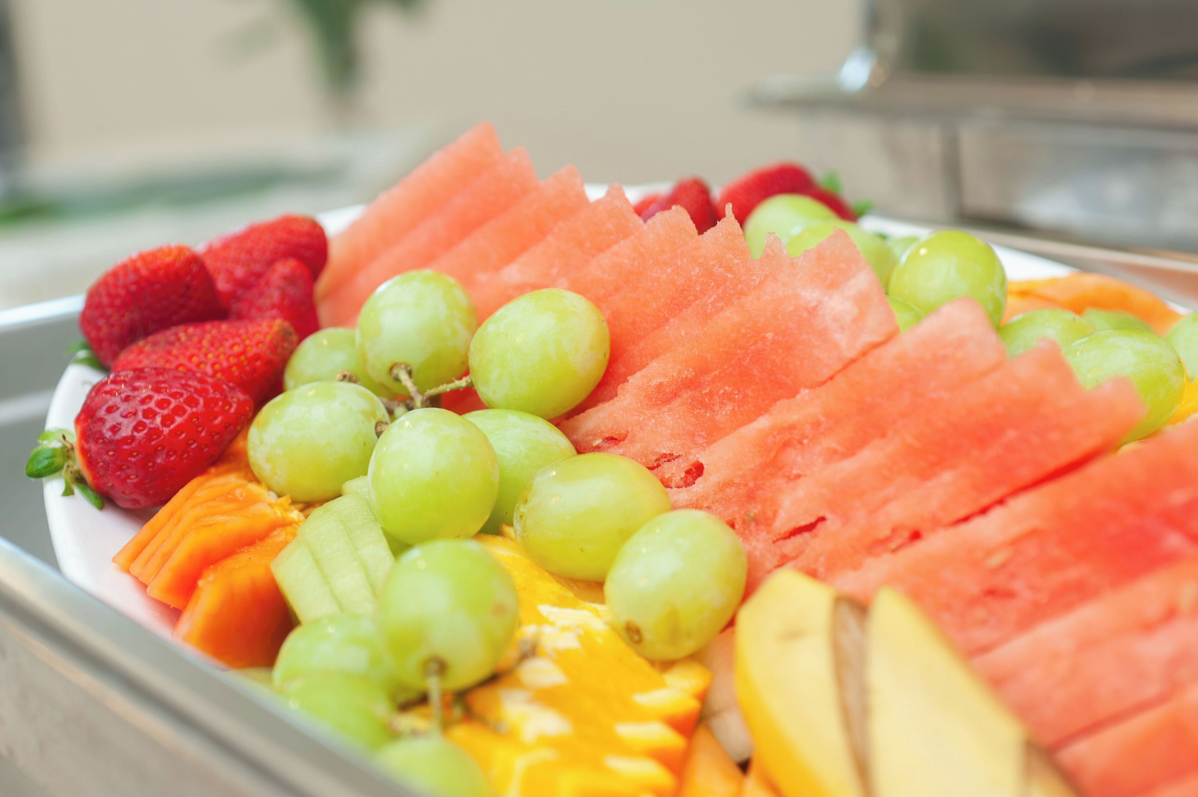A fruit platter with strawberries, grapes, watermelon, and mango slices.