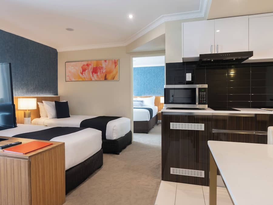 Une chambre d’hôtel avec deux lits, une télévision, un bureau, un four à micro-ondes et une kitchenette.