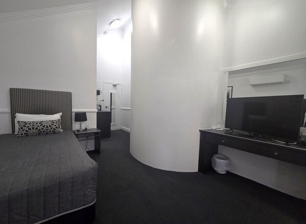 A hotel room with a bed, a desk, a television, and a bathroom. - Comfort Inn & Apartments Northgate Airport (Northgate)