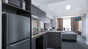 Habitación de hotel compacta con kitchenette, una cama, un escritorio pequeño y vista a un paisaje pintoresco por la ventana.