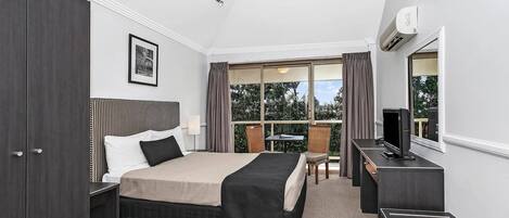 A hotel room with a bed, a desk, a TV, a wardrobe, and a balcony with a table and chairs.