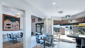 A modern dining area with a wooden floor, blue chairs, and a large painting on the wall.
