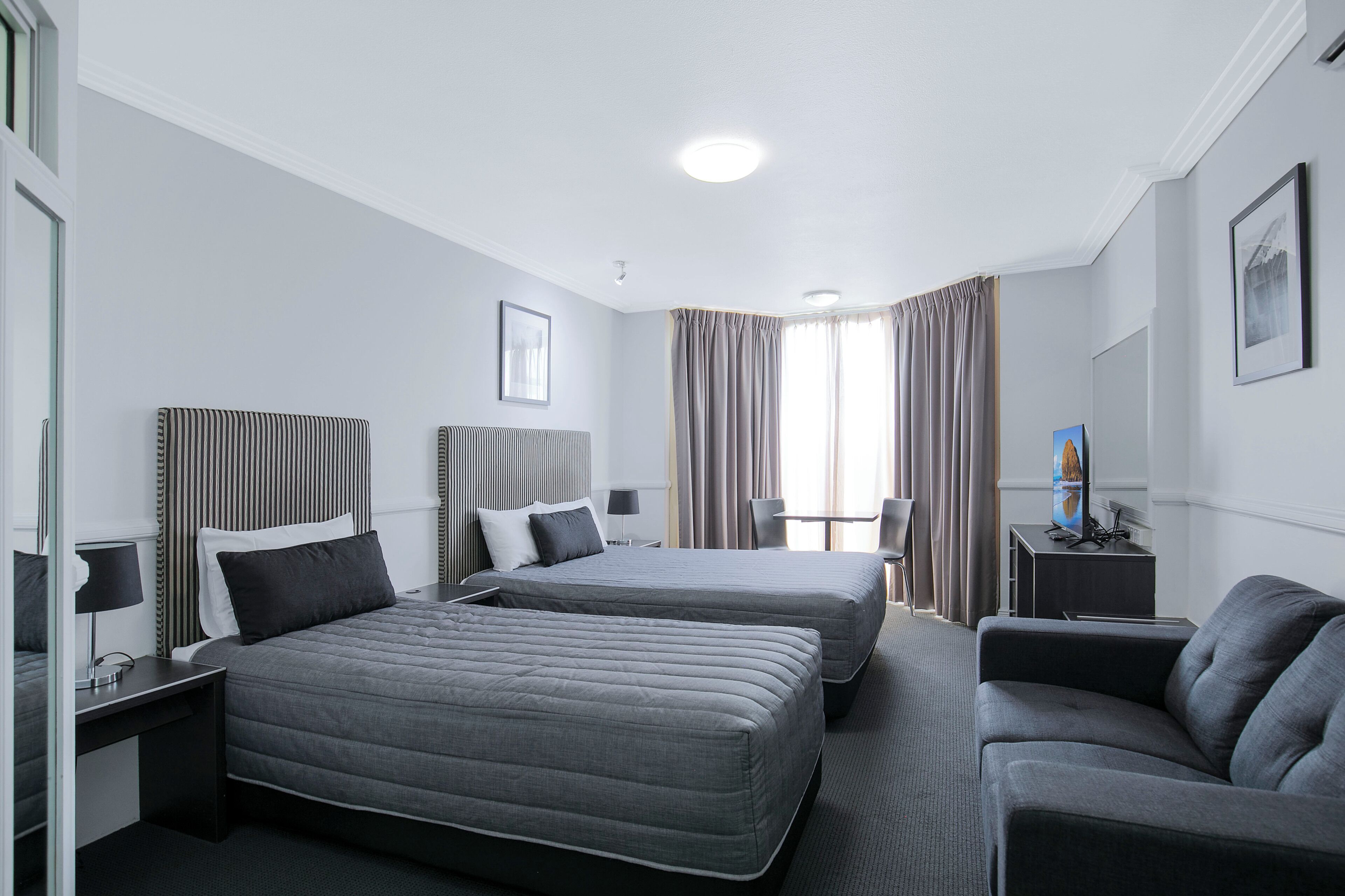 Una habitación de hotel con dos camas, un sofá, un escritorio y una silla.