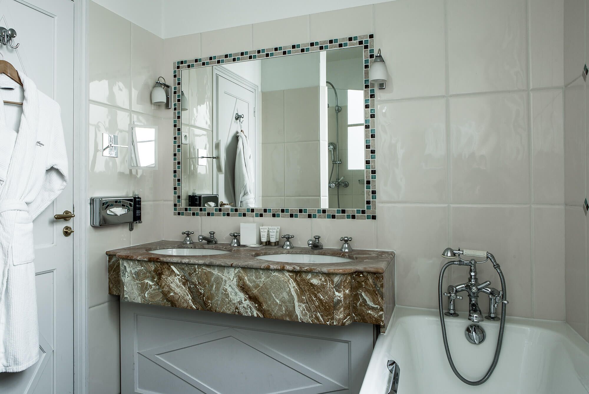 Une salle de bain avec deux lavabos, un grand miroir et une baignoire.
