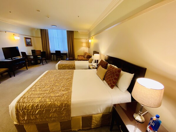Habitación de hotel con dos camas, un escritorio, un televisor y un comedor.