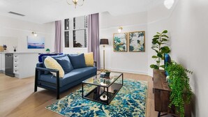 A living room with a sofa, coffee table, and decorative plants. - Royal Albert Hotel (Brisbane)