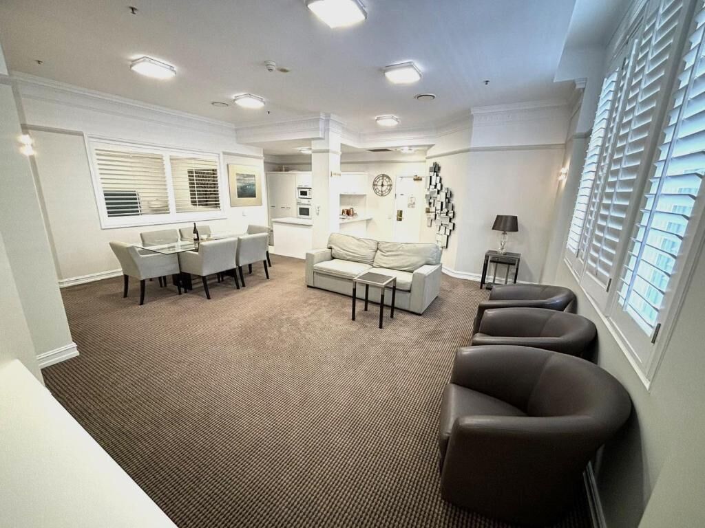 Uma sala de estar moderna com sofá, cadeiras, mesa de centro e um espaço de jantar com mesa e cadeiras.