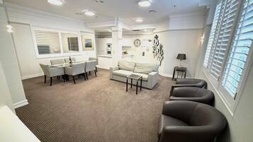 Uma sala de estar moderna com sofá, cadeiras, mesa de centro e um espaço de jantar com mesa e cadeiras.