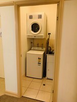 Un cuarto de lavandería con lavadora y secadora, un mueble pequeño y un perchero para toallas.
