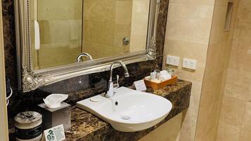 Un baño con un espejo grande, lavabo, ducha y encimera de mármol.