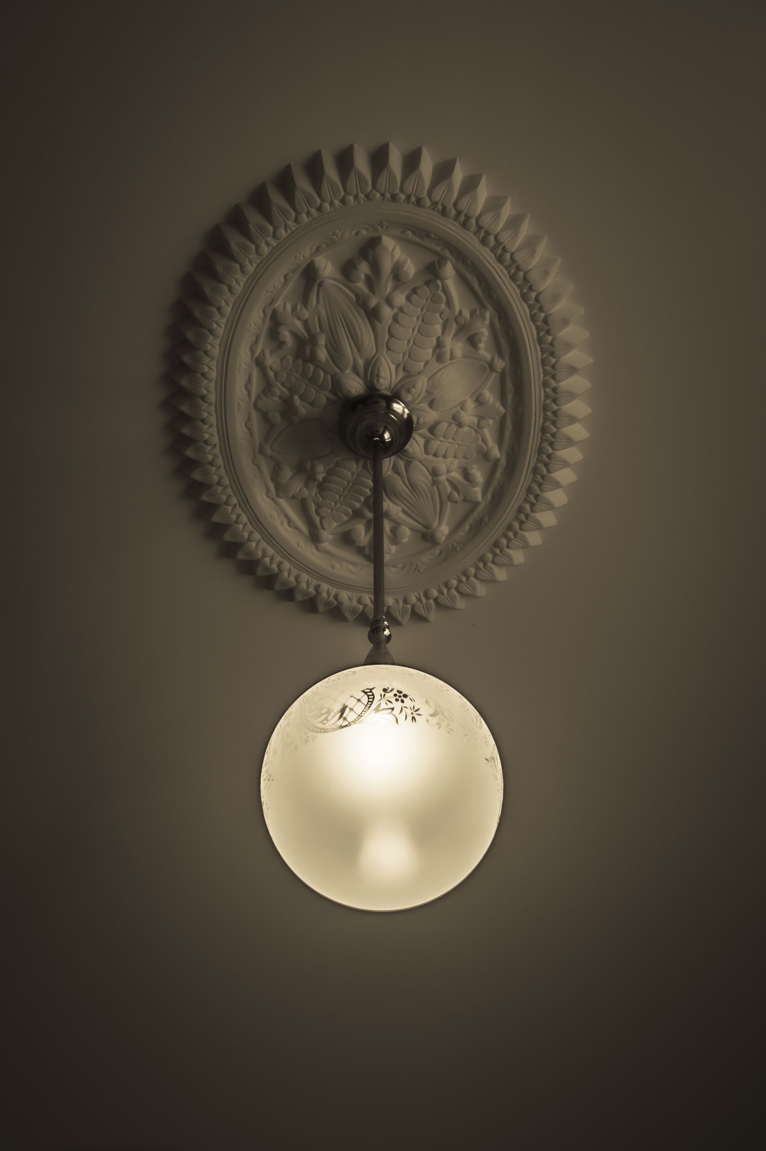 Una lámpara de pared con una placa decorativa y un capuchón esférico.