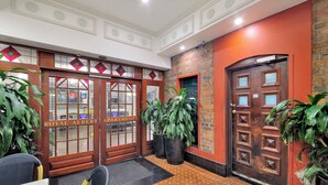 A hotel entrance with a red brick wall, wooden doors, and large potted plants. - Royal Albert Hotel (Brisbane)