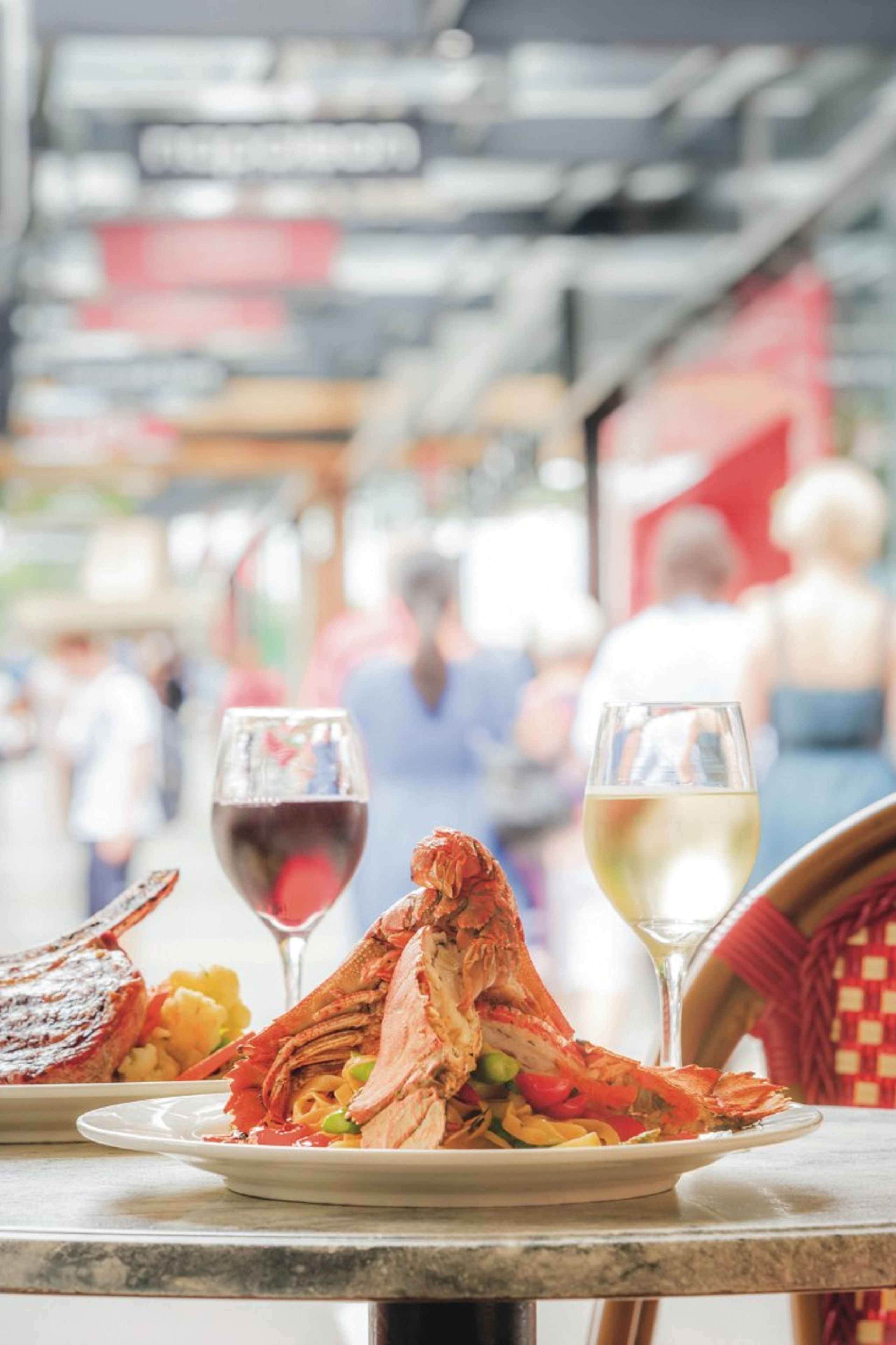 A seafood dish with a lobster tail, a grilled steak, and a glass of red wine on a table.