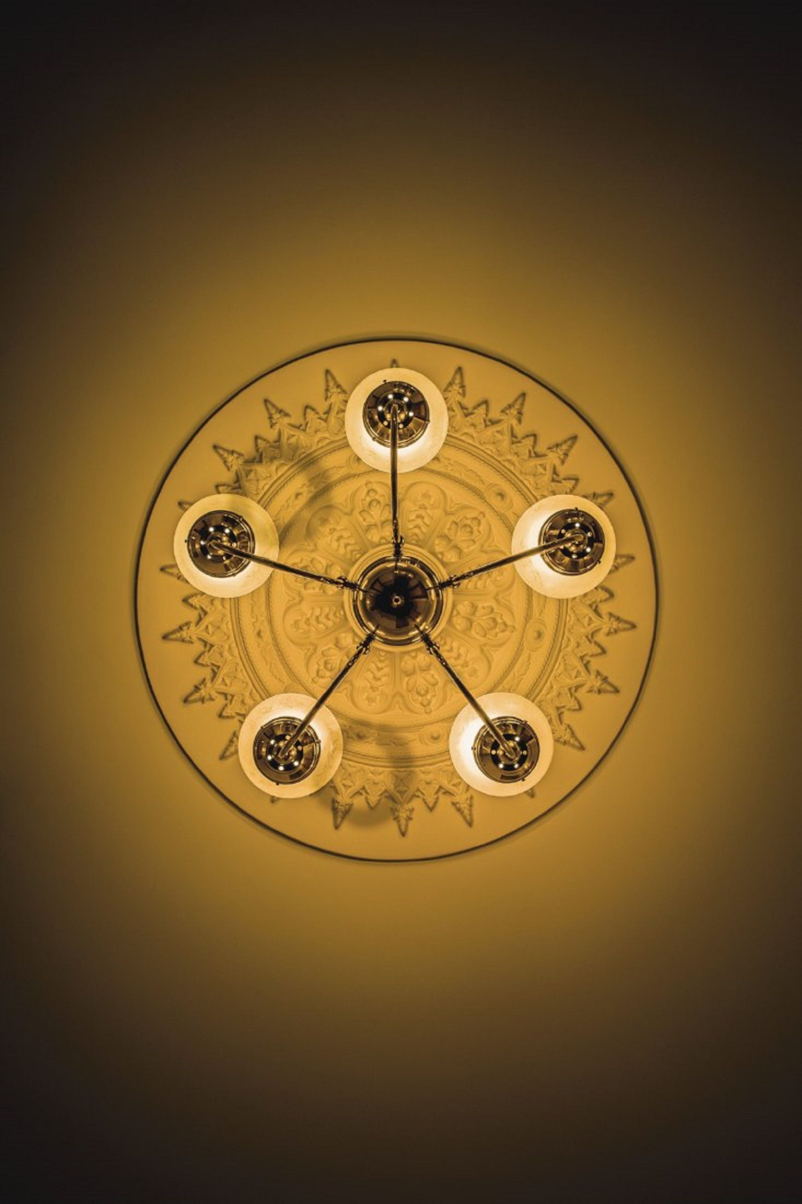 Een plafond met een rond ontwerp, bestaande uit een centraal medaillon en vier hanglampen.