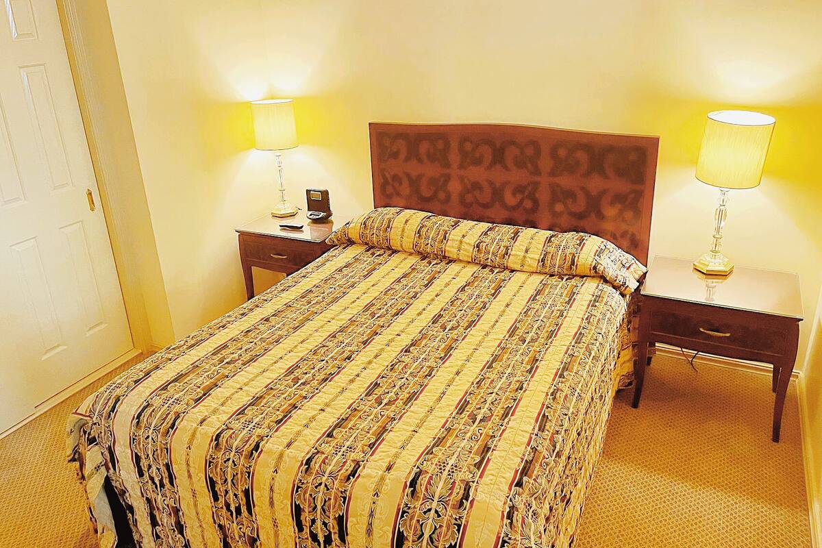 A hotel room with a large bed, two bedside tables with lamps, a wooden headboard, and a door.