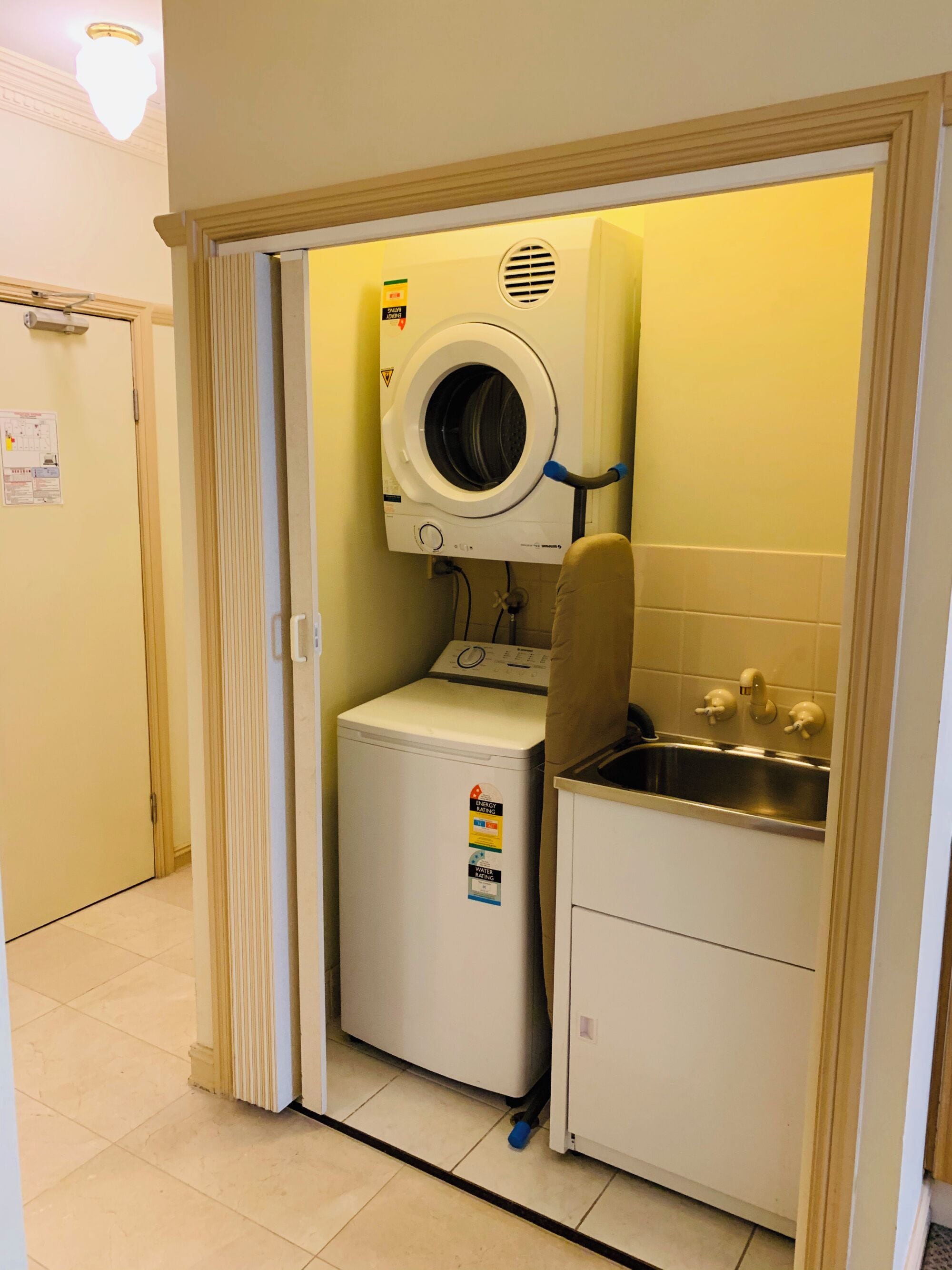 Een kleine wasruimte met een wasmachine, een droger en een wasbak.