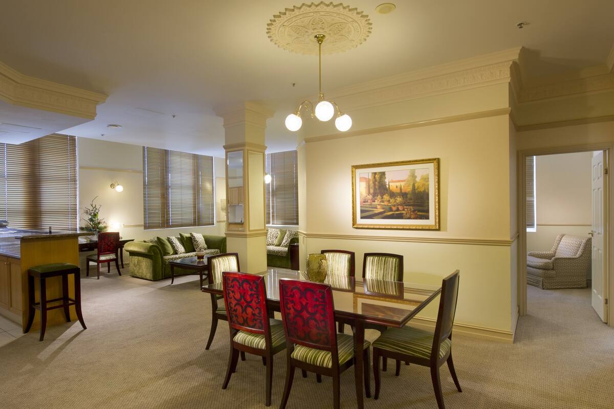 A dining area with a table and chairs, a sofa, and a painting on the wall.