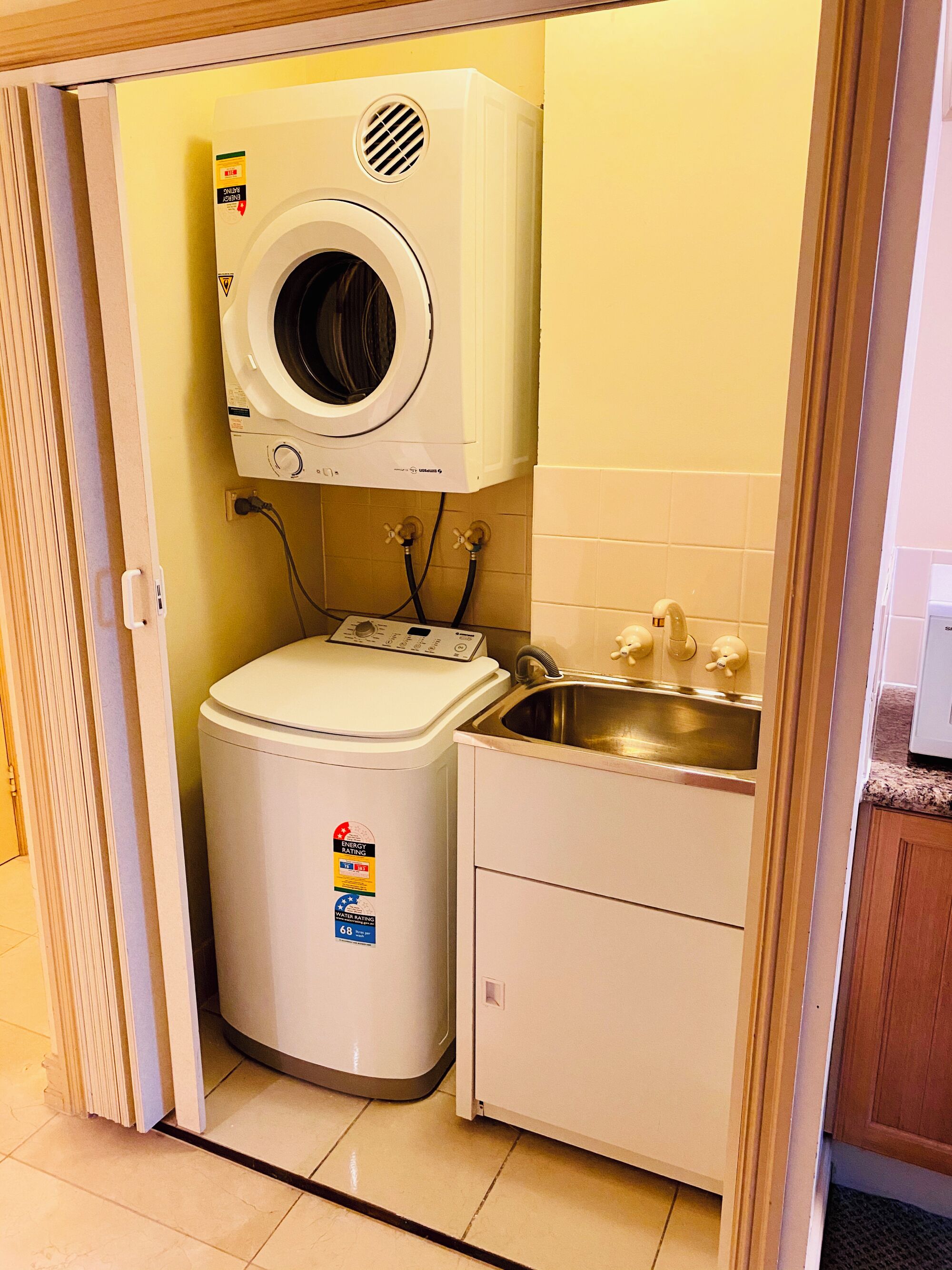 A compact laundry room with a washing machine, a dryer, and a sink.