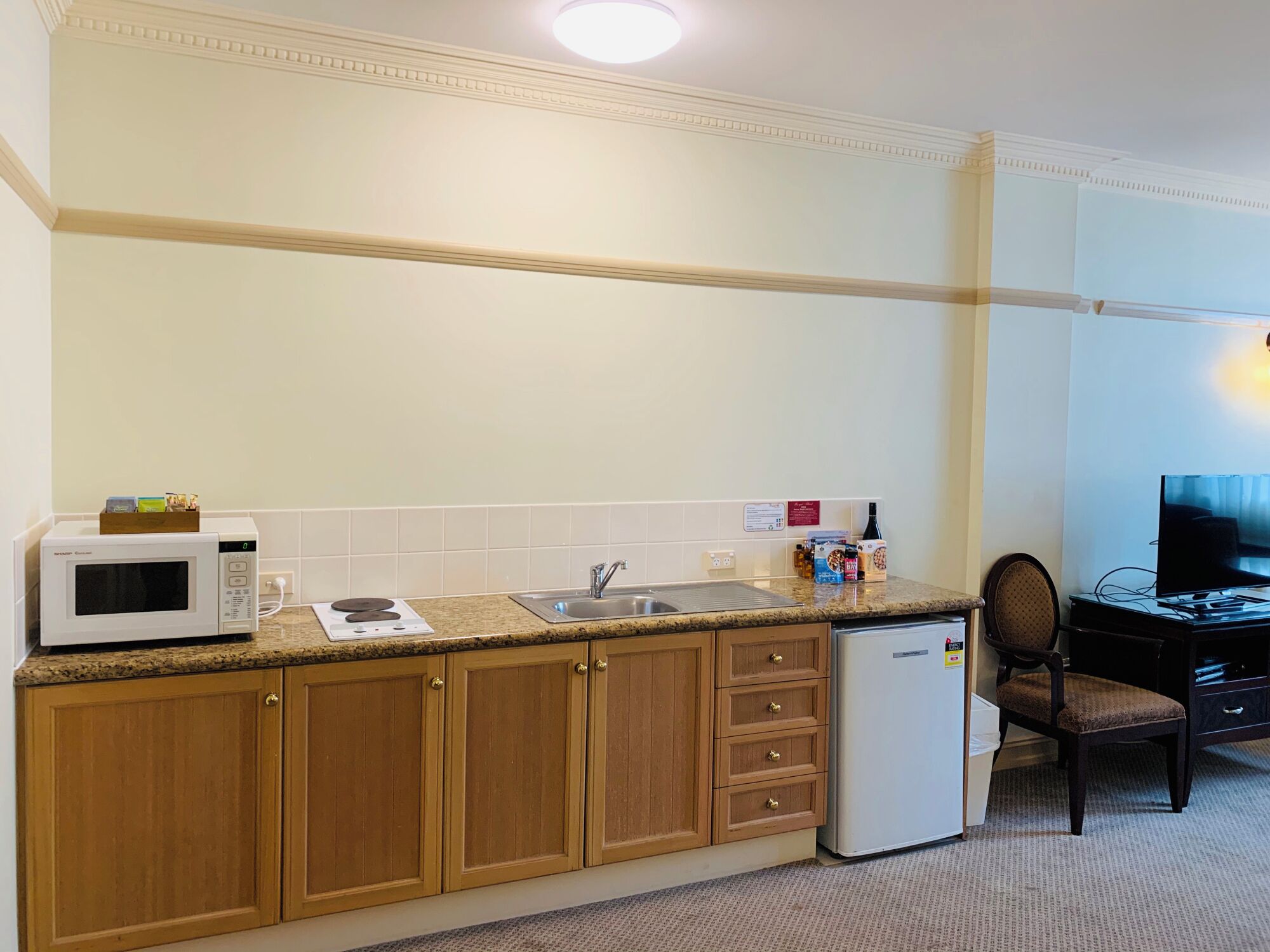 A compact kitchen with a microwave, stove, sink, and refrigerator.