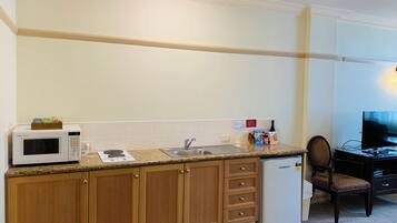 A compact kitchen with a microwave, stove, sink, and refrigerator.