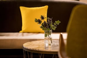 A round table with a vase containing flowers, placed on a sofa with a yellow pillow. - Renaissance Paris Vendome Hotel (Paris)