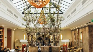 A spacious lobby with a high ceiling, a central seating area, and a large tree. - Renaissance Paris Vendome Hotel (Paris)