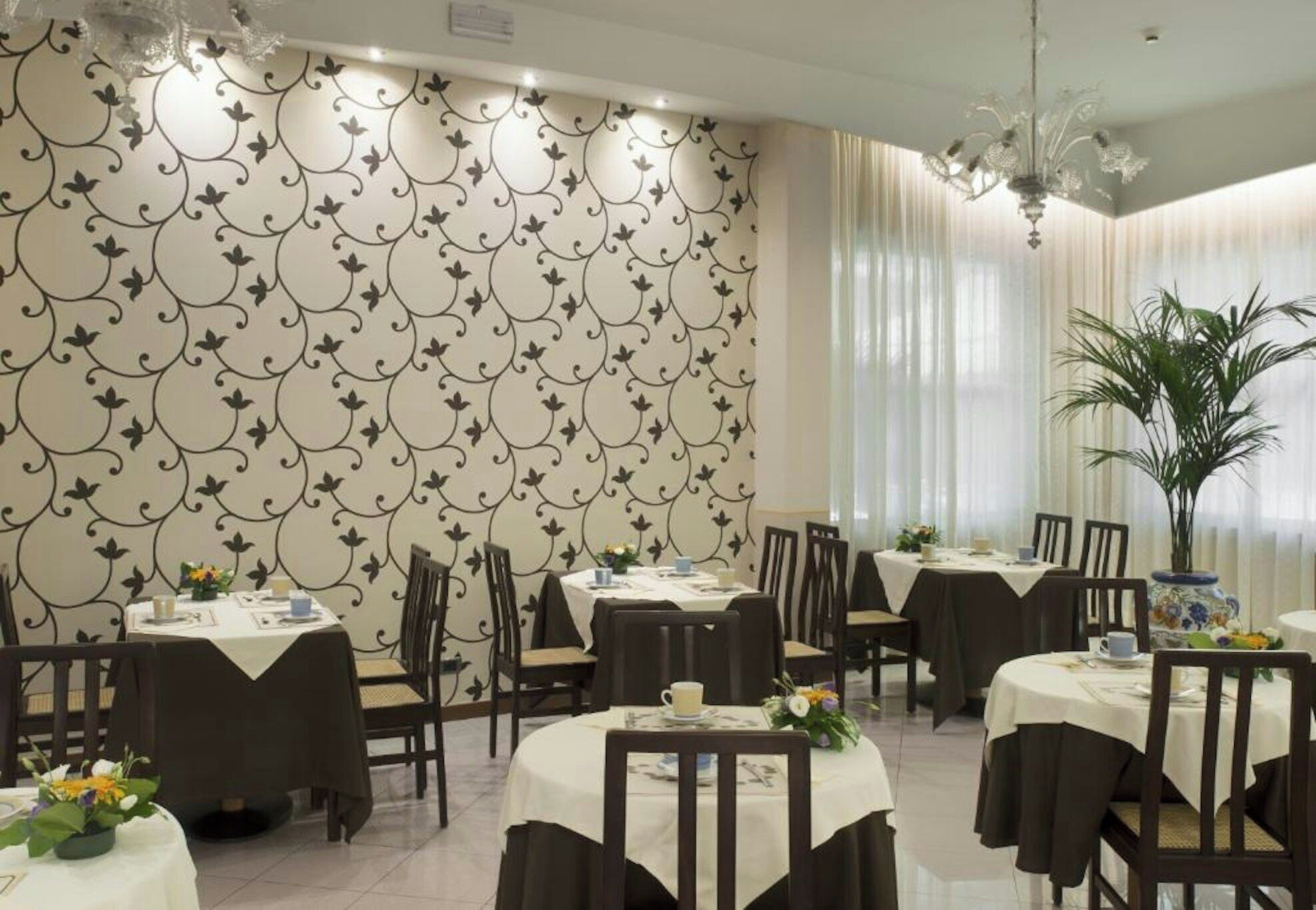 A restaurant with round tables, chairs, and a patterned wallpaper.