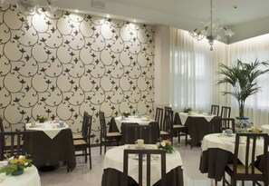 A restaurant with round tables, chairs, and a patterned wallpaper.