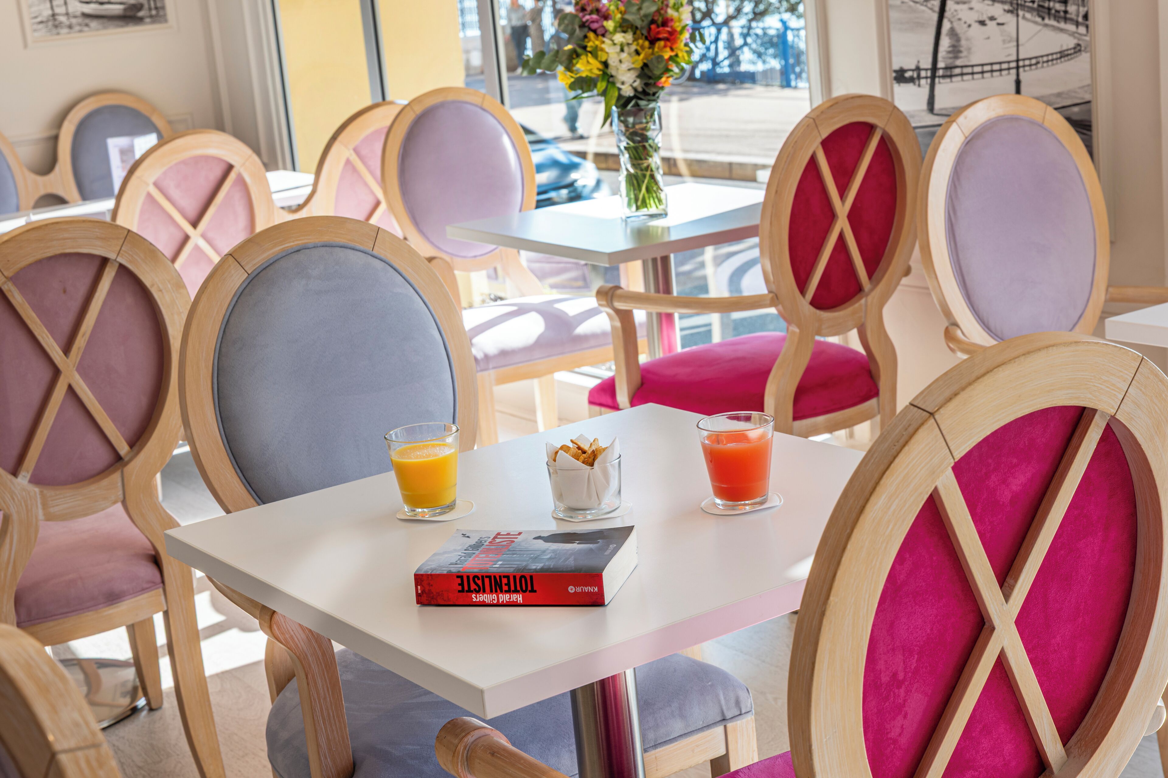 A dining area with wooden chairs, a white table, and a book titled "Toulouse".