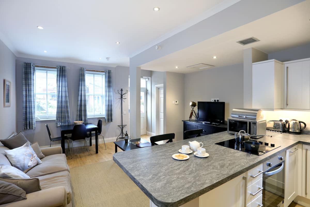 A modern kitchen with a central island, dining area, and a cozy seating space.
