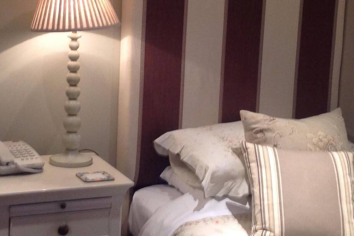 A neatly made bed with striped pillows, a bedside lamp, and a telephone on a bedside table.