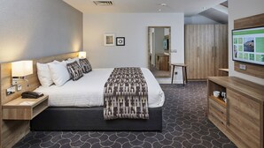 A modern hotel room with a large bed, bedside tables, a desk, and a wardrobe.