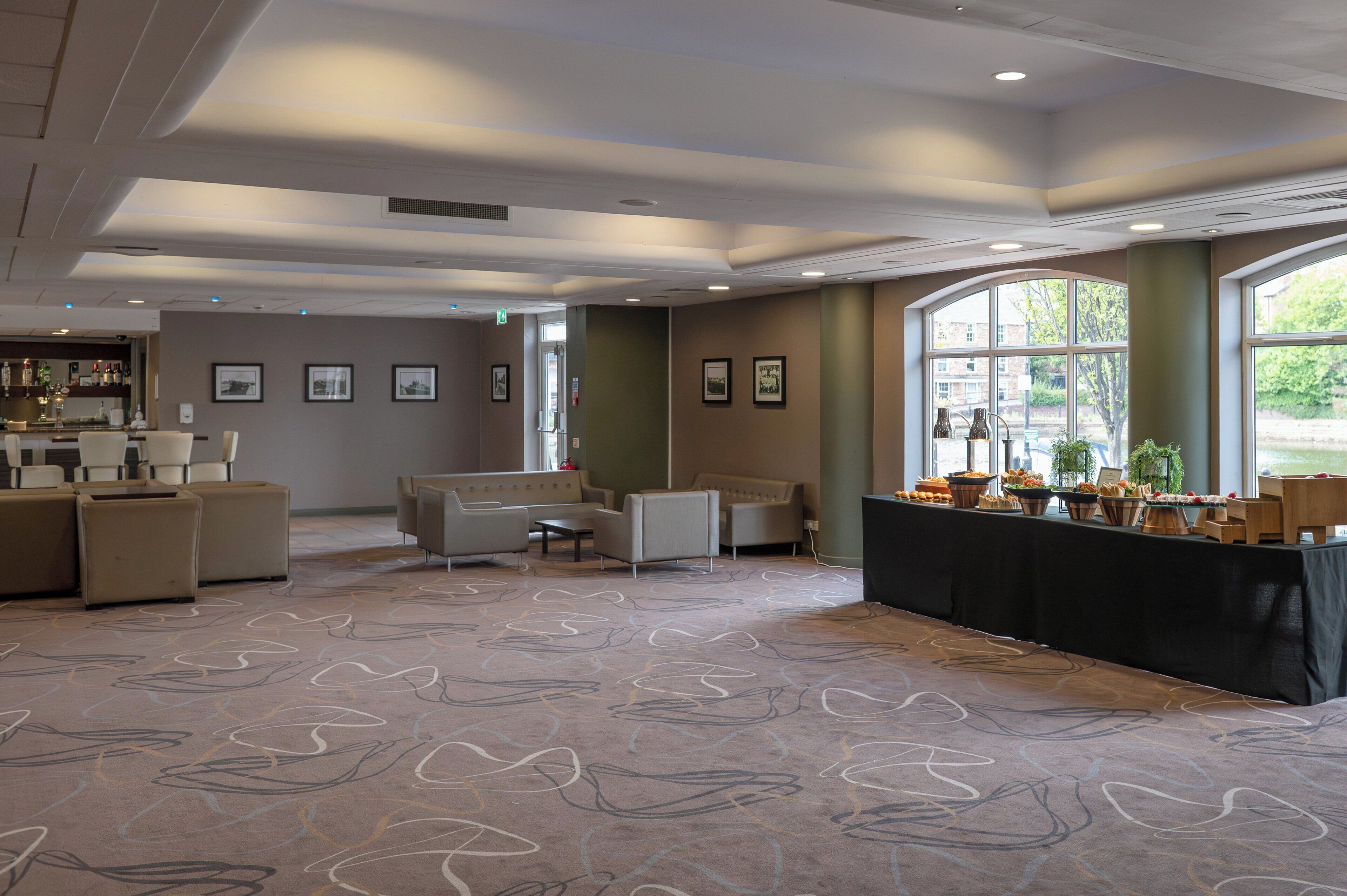 A spacious room with a long table, sofas, and a bar area.
