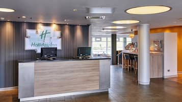 Un moderno vestíbulo de hotel con mostrador de recepción, comedor y bar.