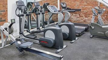 Uma academia com diversos equipamentos de cardio, como esteiras, elípticos, remo e bicicleta ergométrica.
