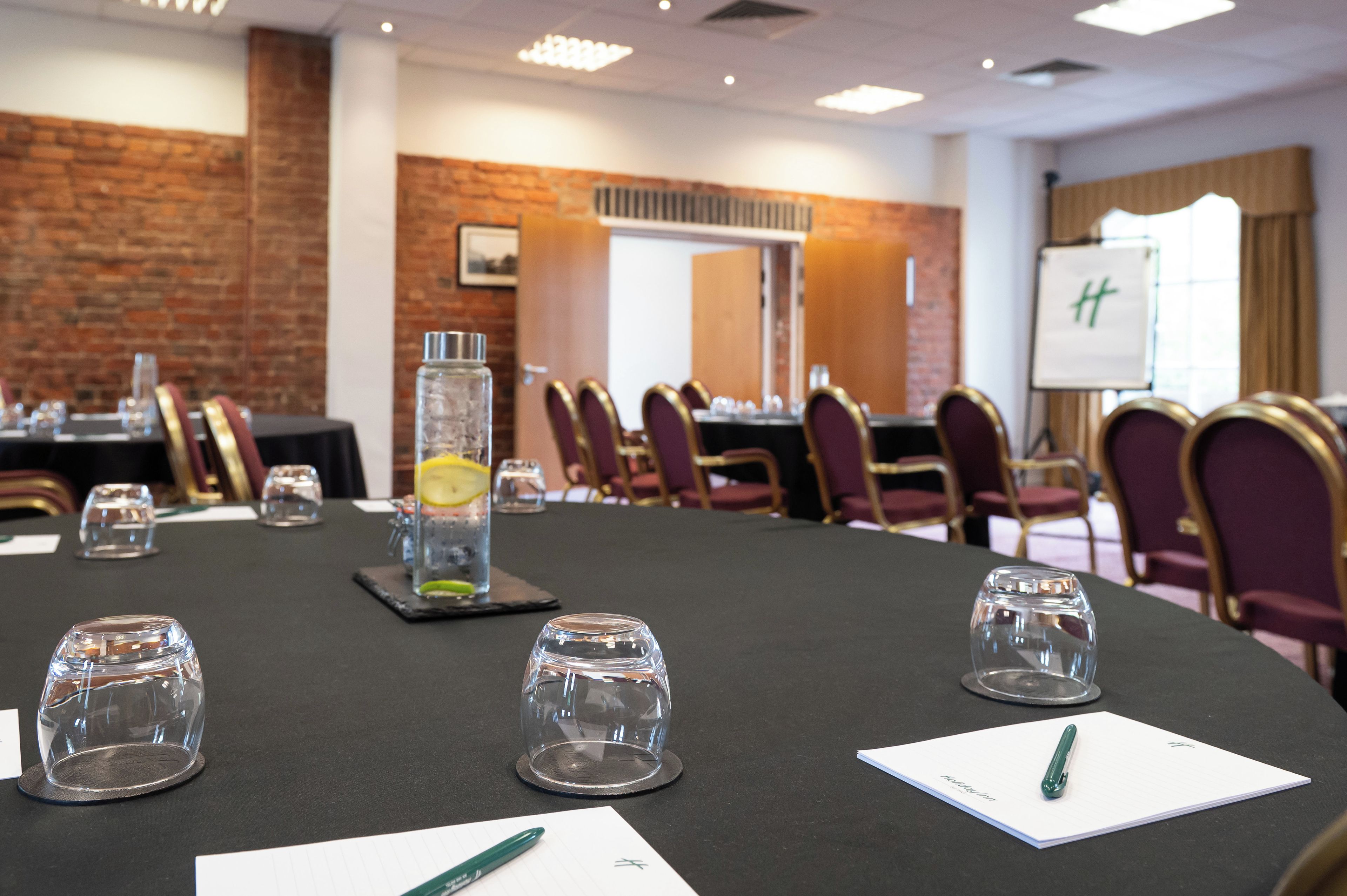 A conference room with a long table, chairs, a whiteboard, and a brick wall.