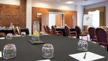 A conference room with a long table, chairs, a whiteboard, and a brick wall.