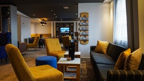 A hotel lobby with a sofa, chairs, a TV, and a wall with magazines.