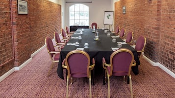A conference room with a long table, chairs, and a whiteboard.