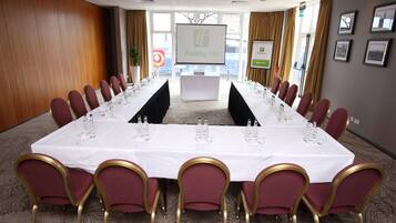 A conference room with a long table set for a meeting, surrounded by chairs, a screen, and framed pictures on the walls.