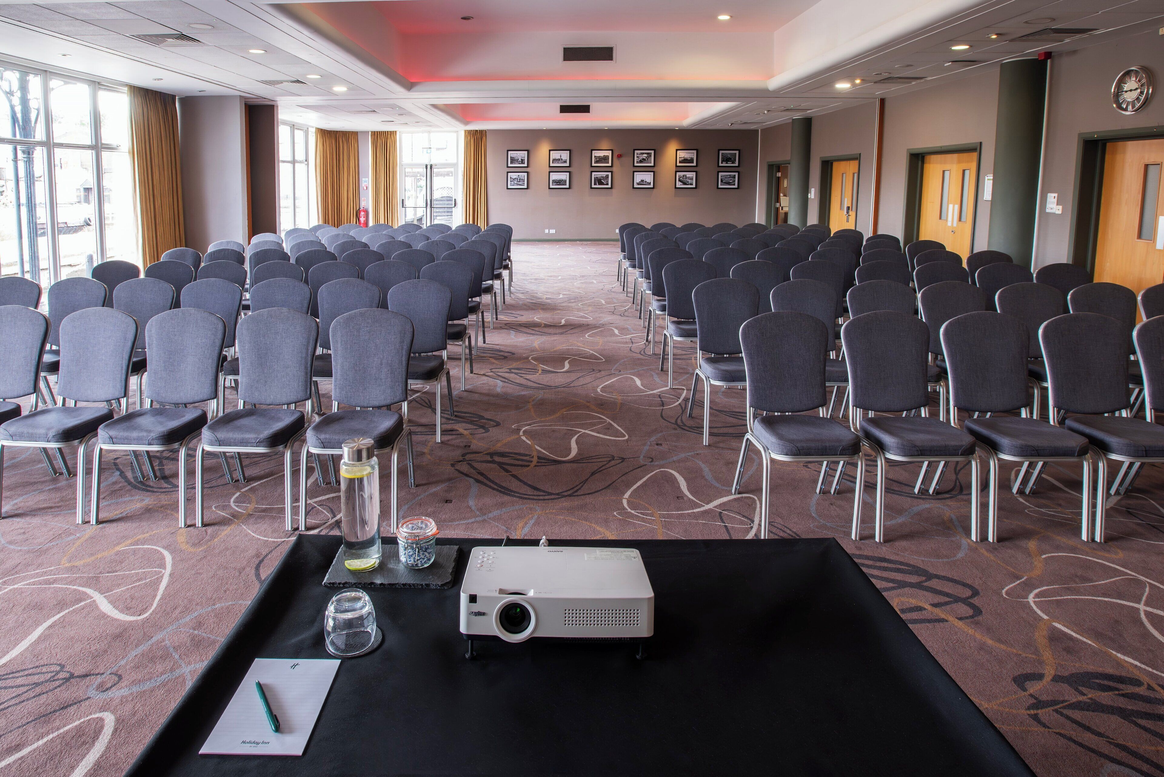 A conference room with rows of chairs, a projector, and a presentation table.