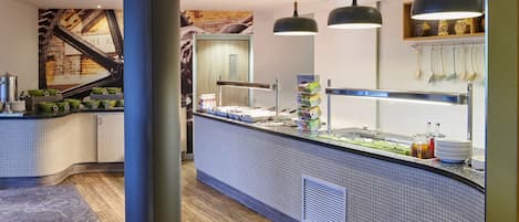A modern kitchen area with a counter, hanging lights, and a tiled backsplash.
