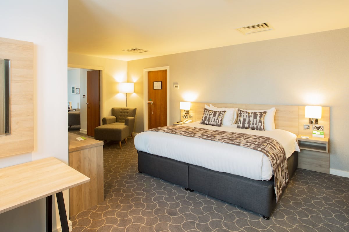 A hotel room with a large bed, bedside tables, a desk, and a chair.