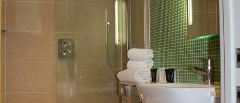 A bathroom with a shower, toilet, sink, and a green-tiled wall.