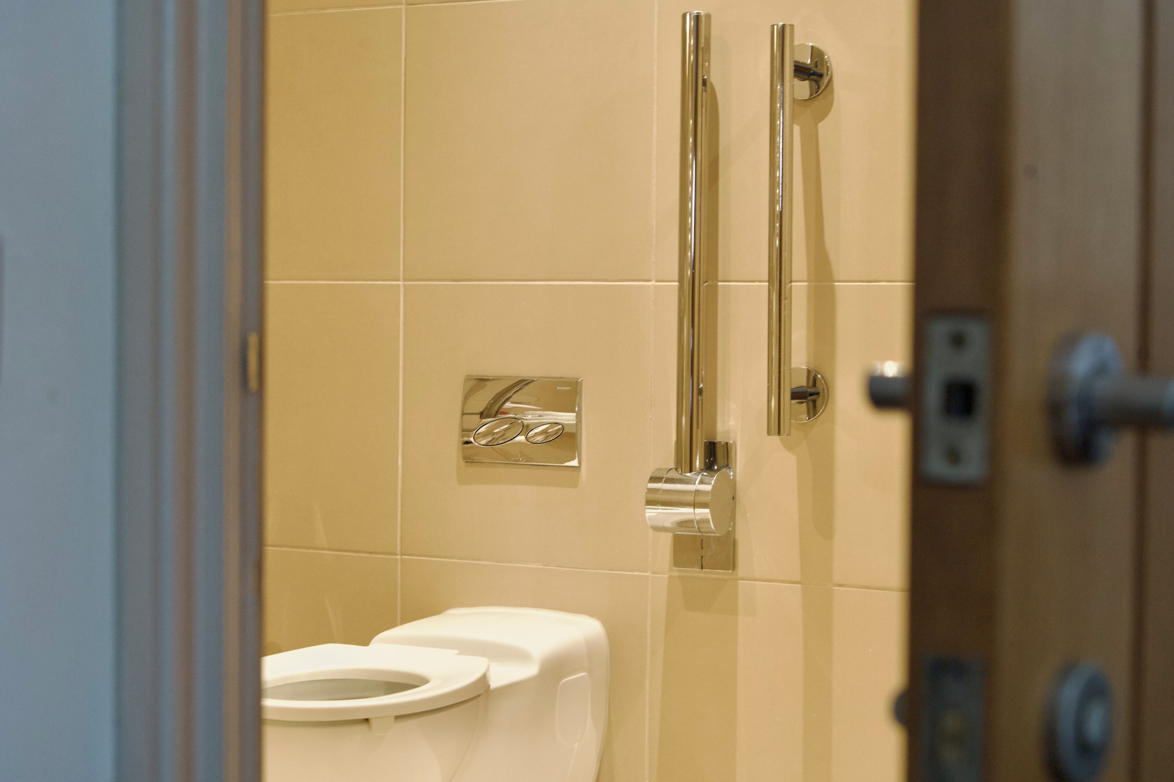 A bathroom with a white toilet, a hand dryer, and a paper towel dispenser.