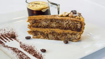 A slice of layered cake with a glass of coffee on a white plate.
