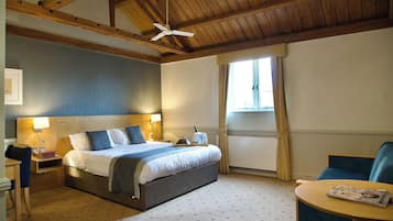 A hotel room with a bed, bedside table, lamp, and a window with curtains.